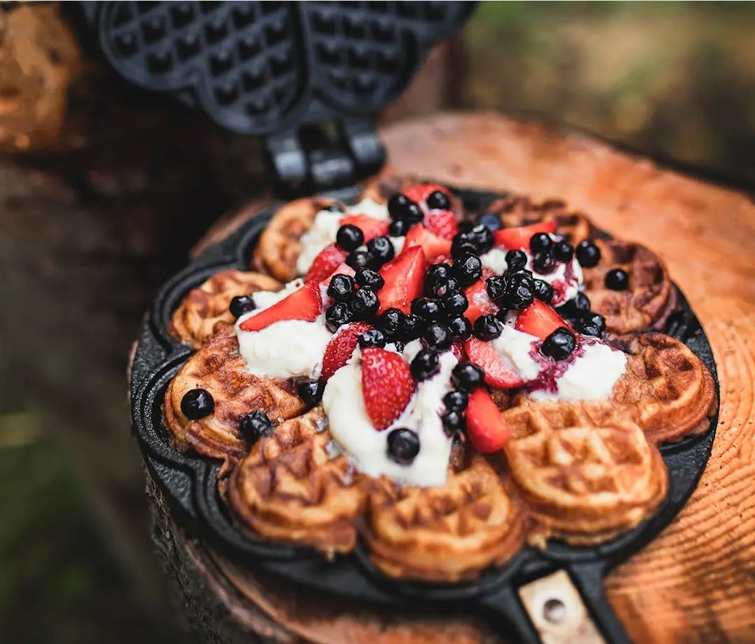 våffeljärn i gjutjärn med en nygräddad våffla med färska bär på