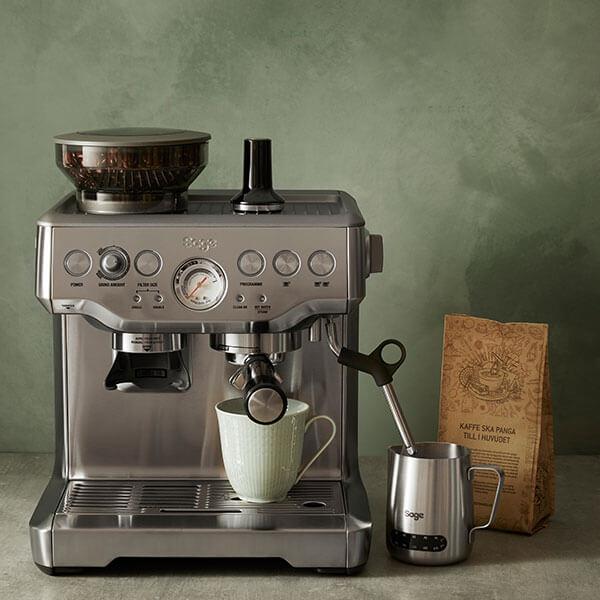 Laadukas espressokone ruostumattomasta teräksestä maidonvaahdotin kahvipavut ja kahvikuppi 