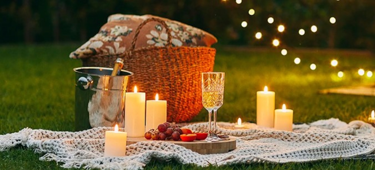 Ljus på romantisk picknickfilt uppdukat med bubbel och vindruvor 