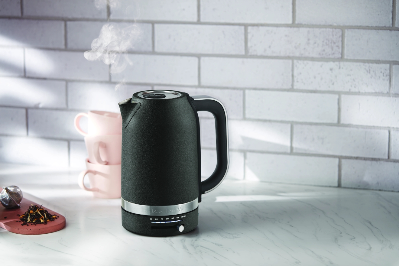 Kitchenaid vattenkokare i svart på en köksbänk av marmor med hett vatten i 