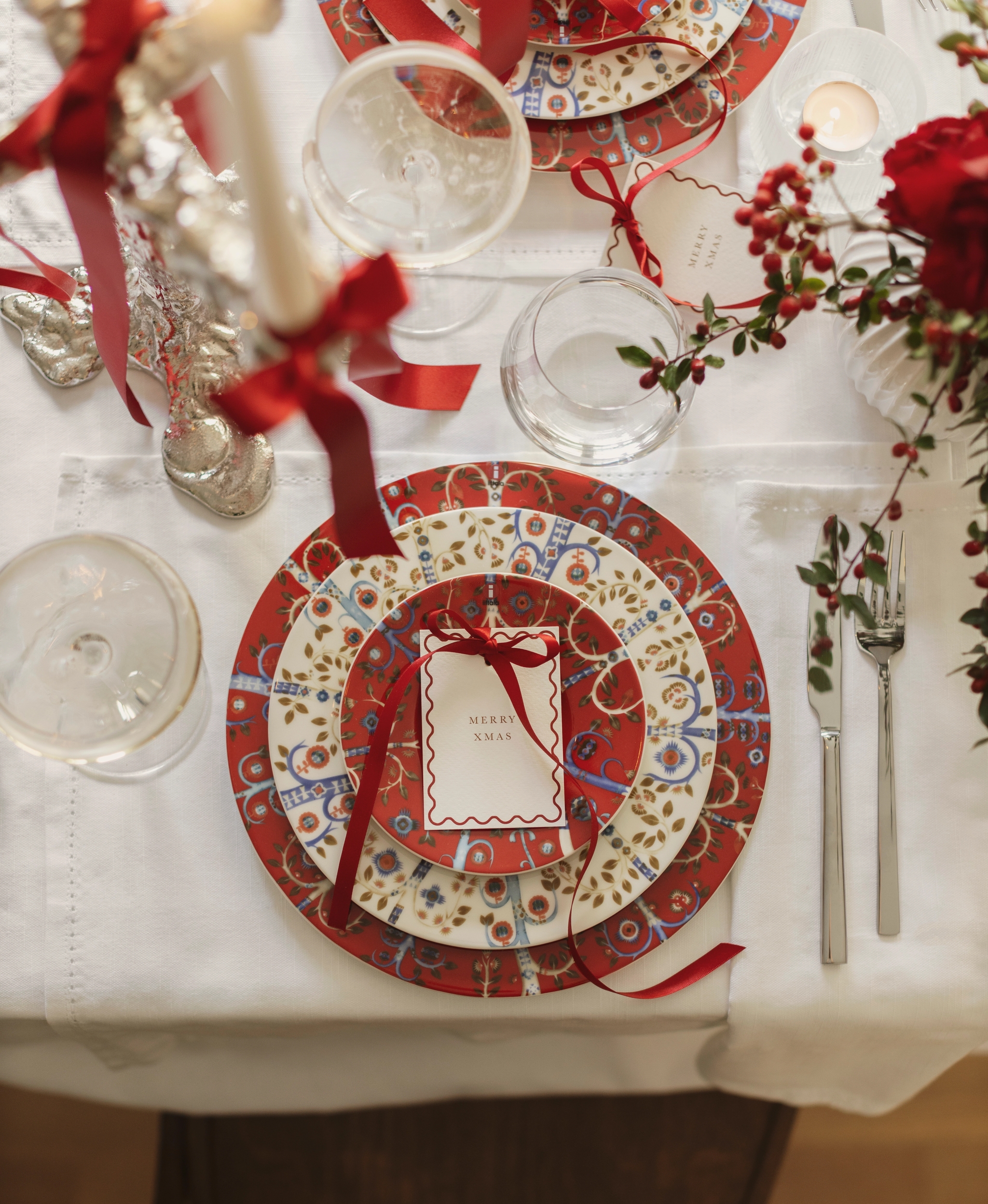 a table set for a christmas dinner with plates , candles , and flowers .
