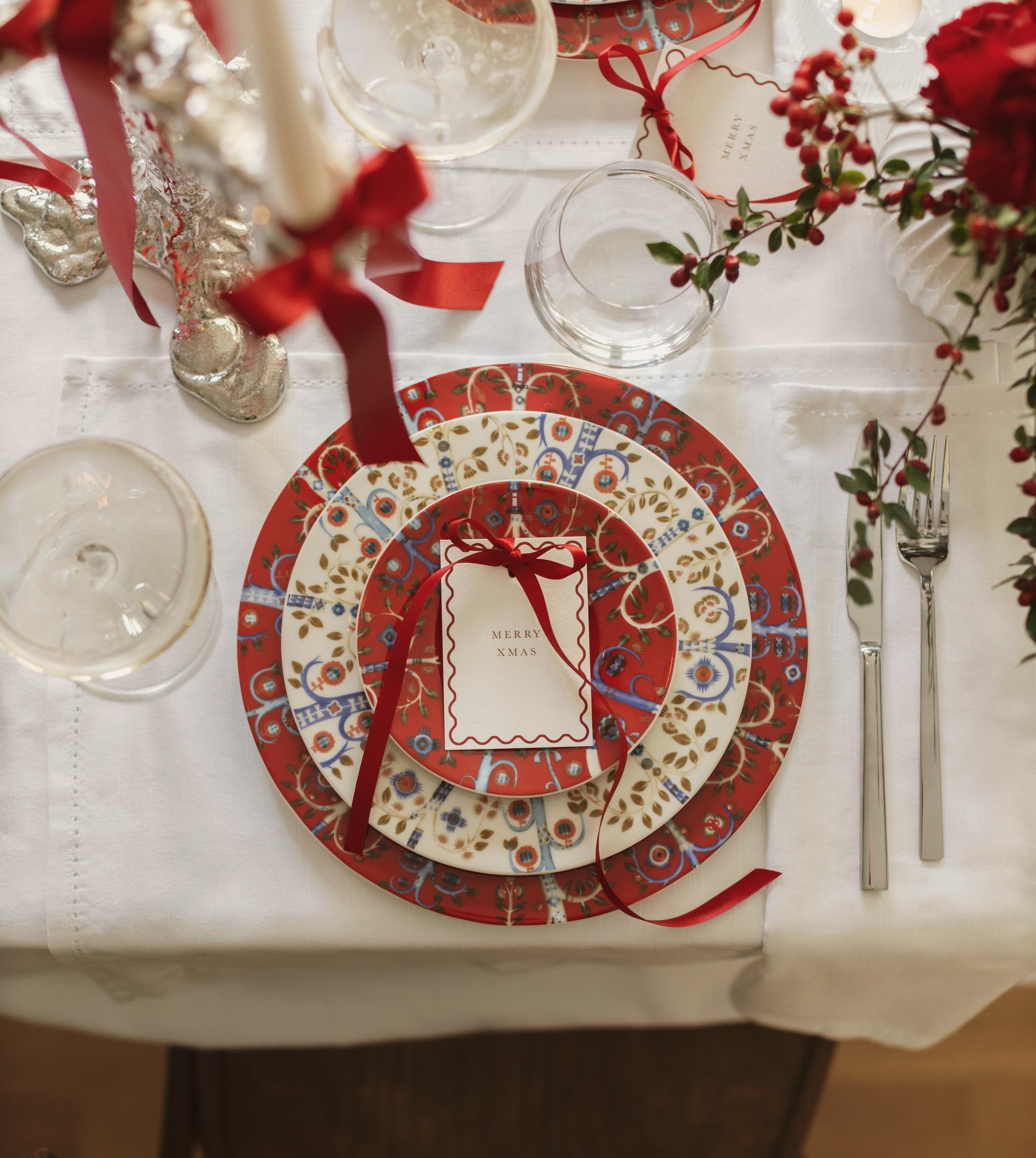 a table set for a christmas dinner with plates , candles , and flowers .