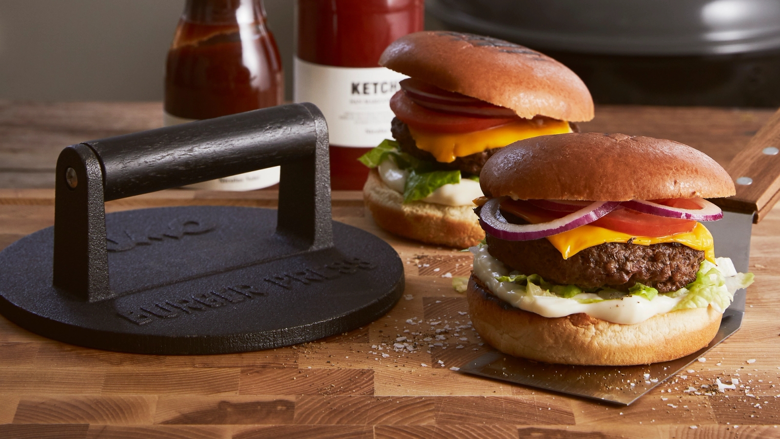 Hamburgerpress med två goda hamburgare på skärbräda