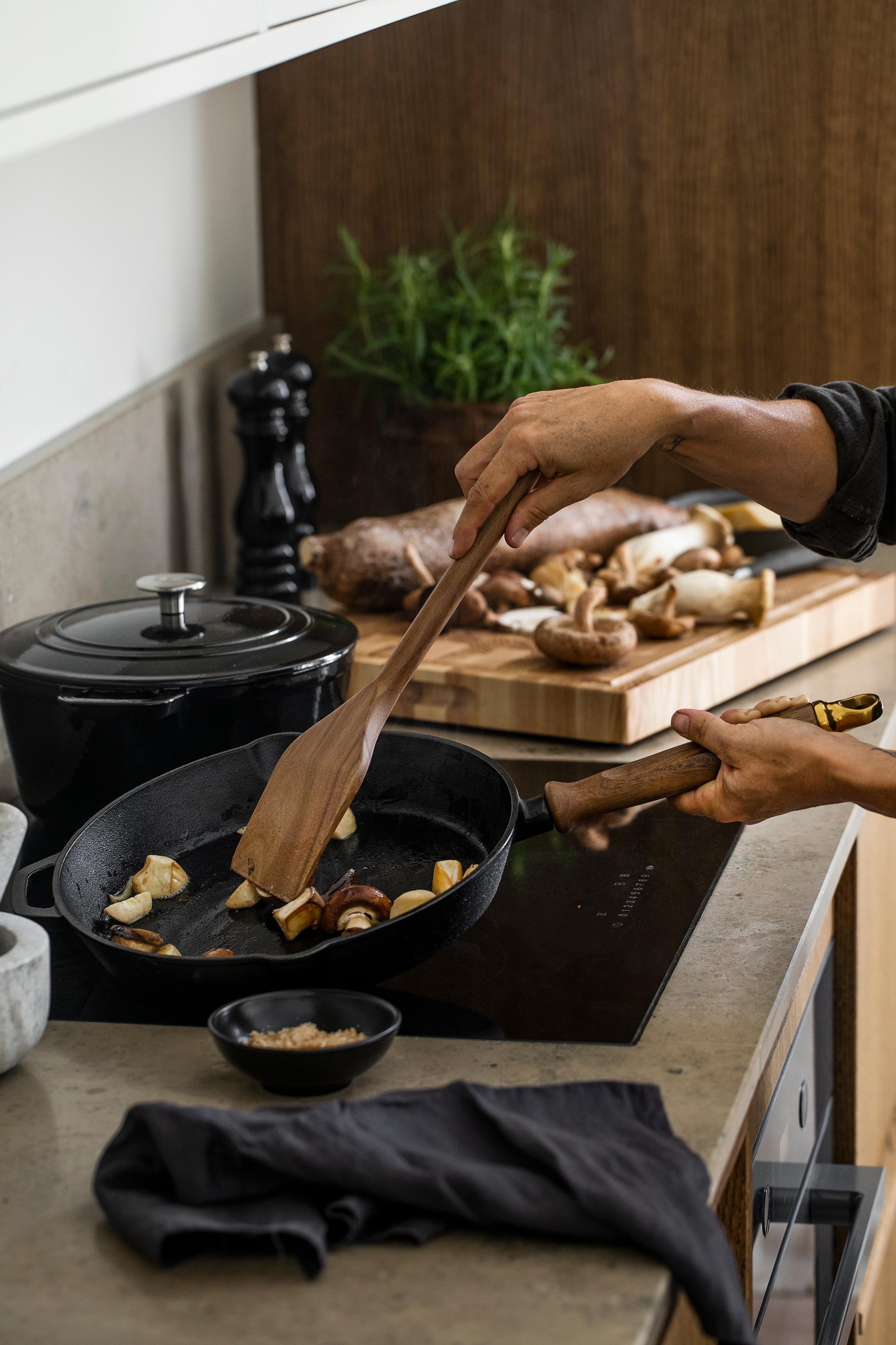 a person is stirring food in a frying pan with a wooden spatula