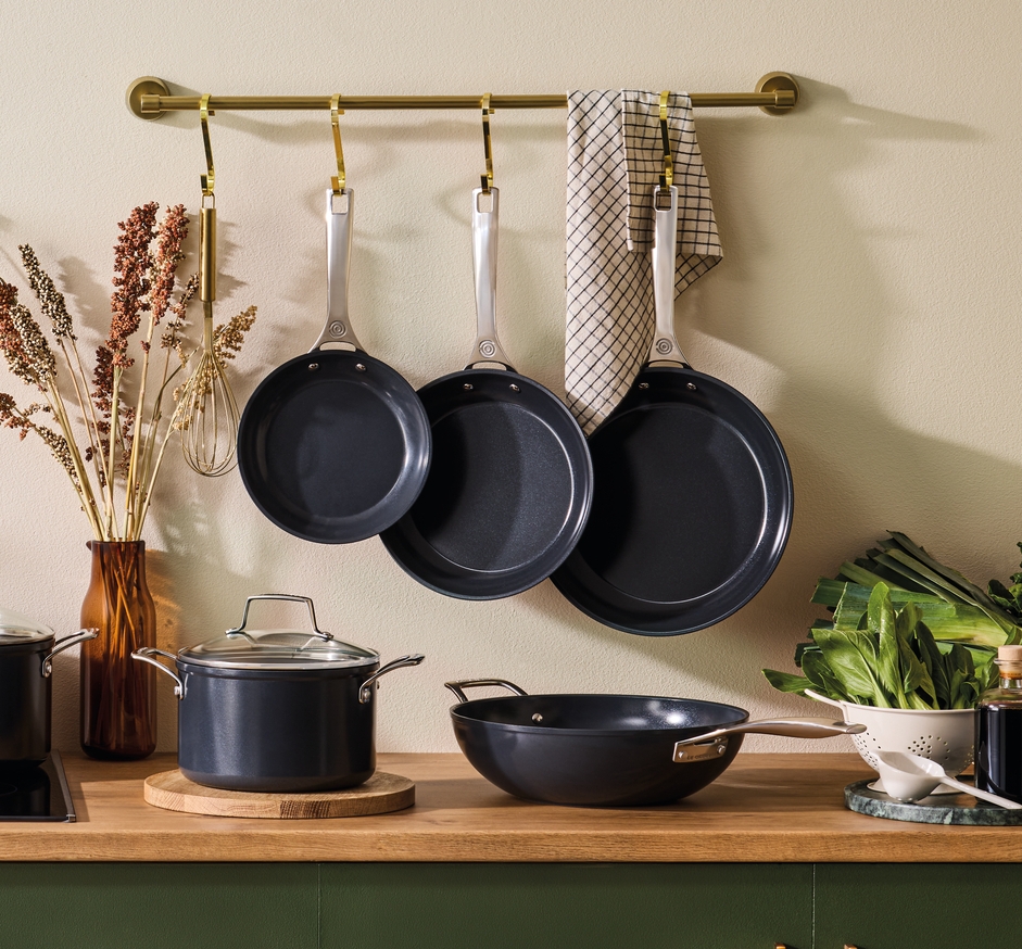 Tyylikäs kokoelma tummanharmaita kattiloita ja pannuja keittiössä.
