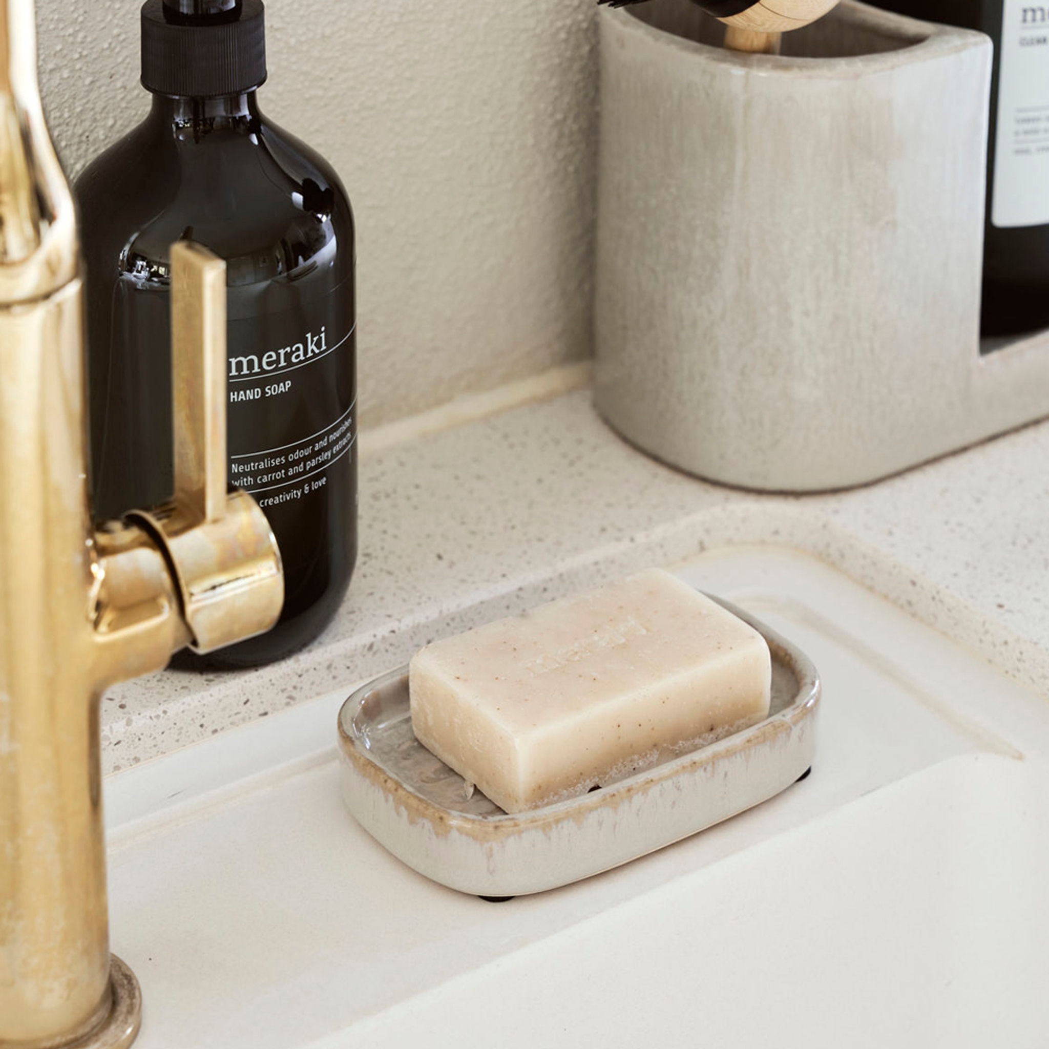 Pumptvål och en hård tvål från Meraki på ett handfat