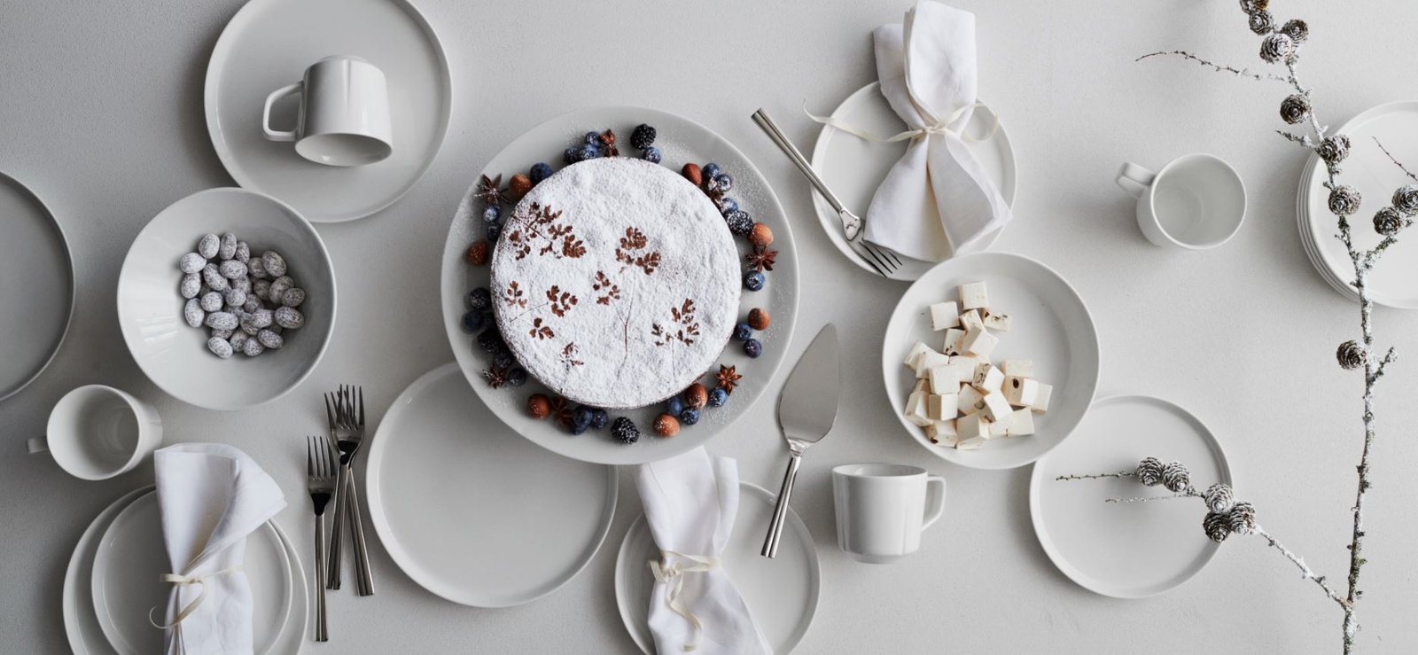 Grand Cru servis i vitt uppdukat på ett bord med tårta och kaffekoppar.