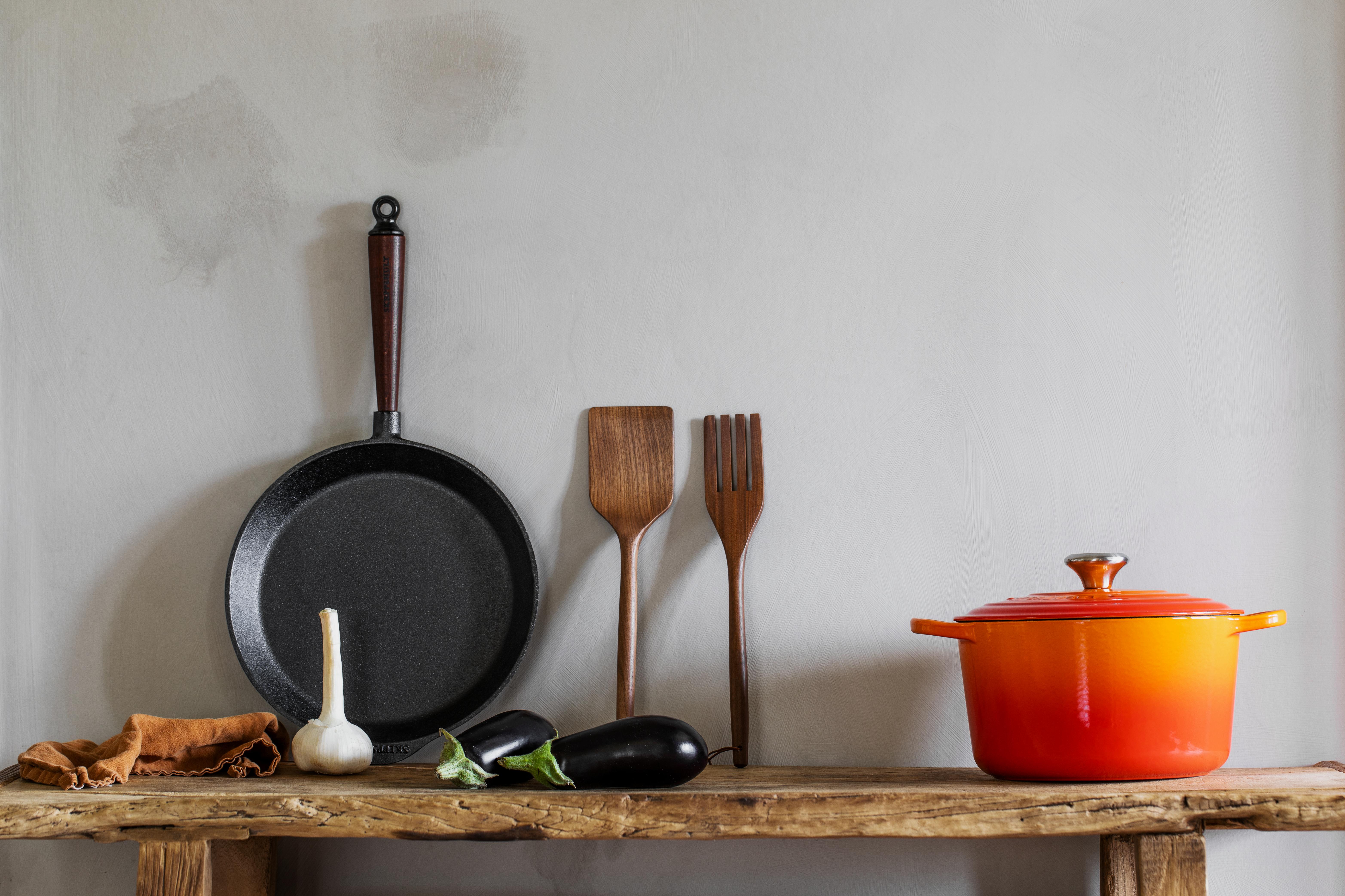 gjutjärnspanna lutad mot väggen med trähandtag