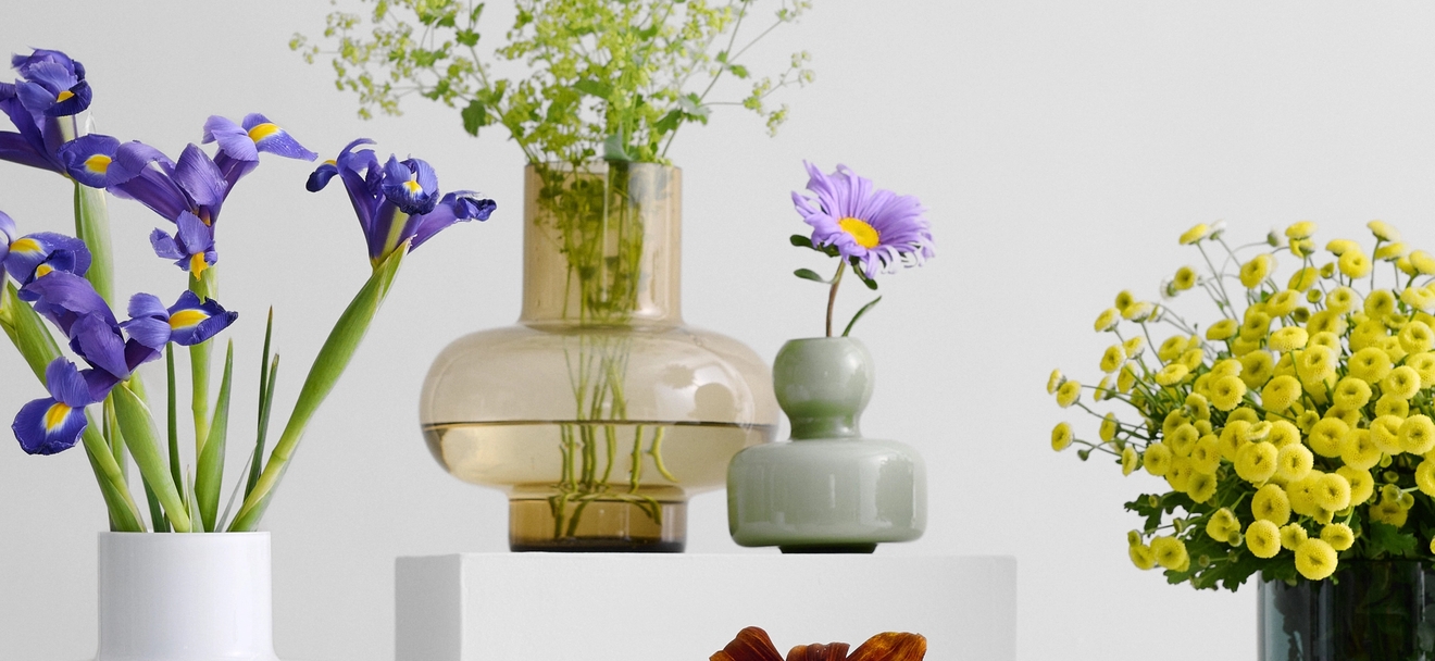 lasinen Marimekko maljakko eri muodoissa ja väreissä eriväristen kukkien kera