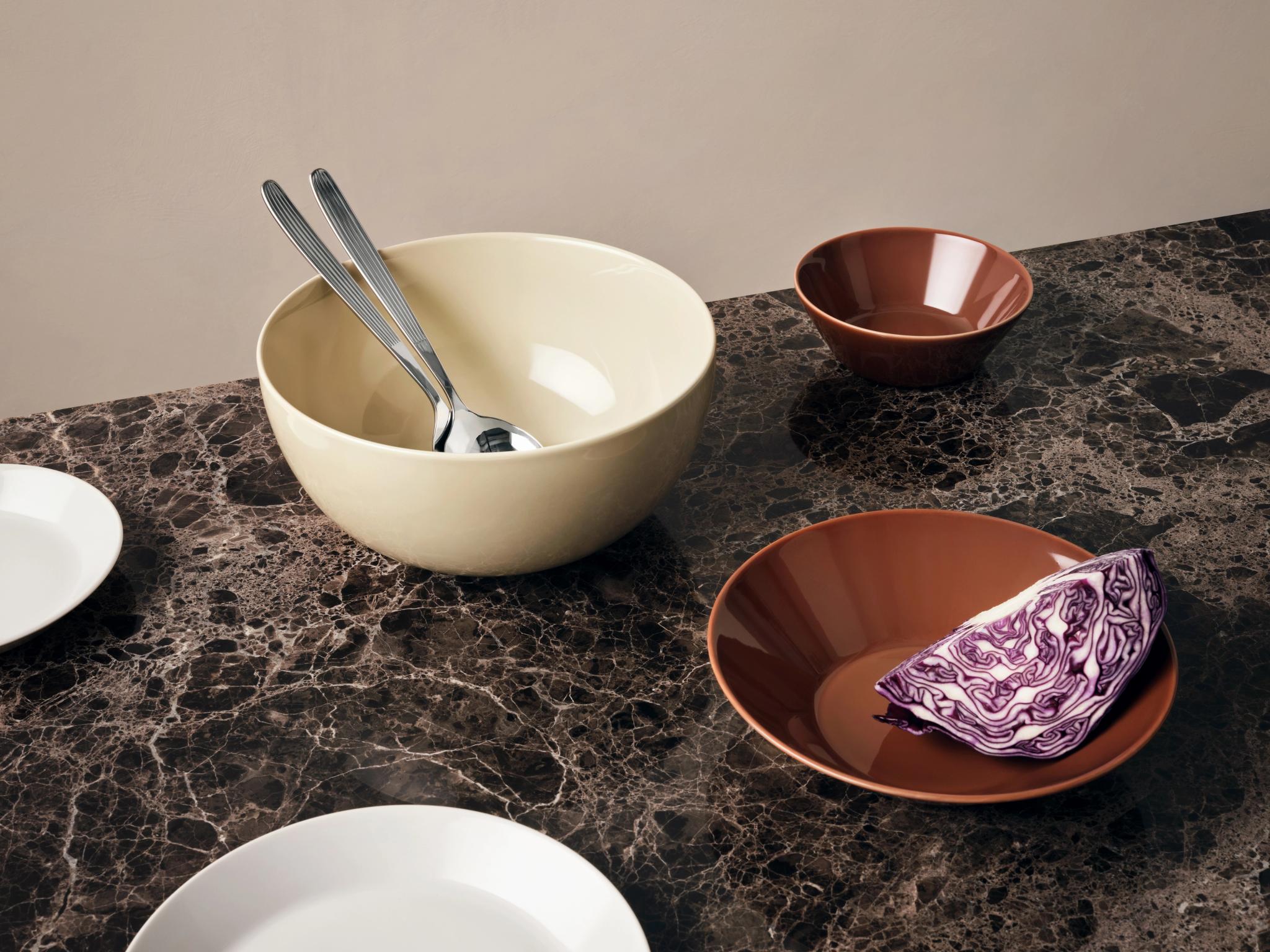 a table topped with plates , bowls , and a slice of cabbage .