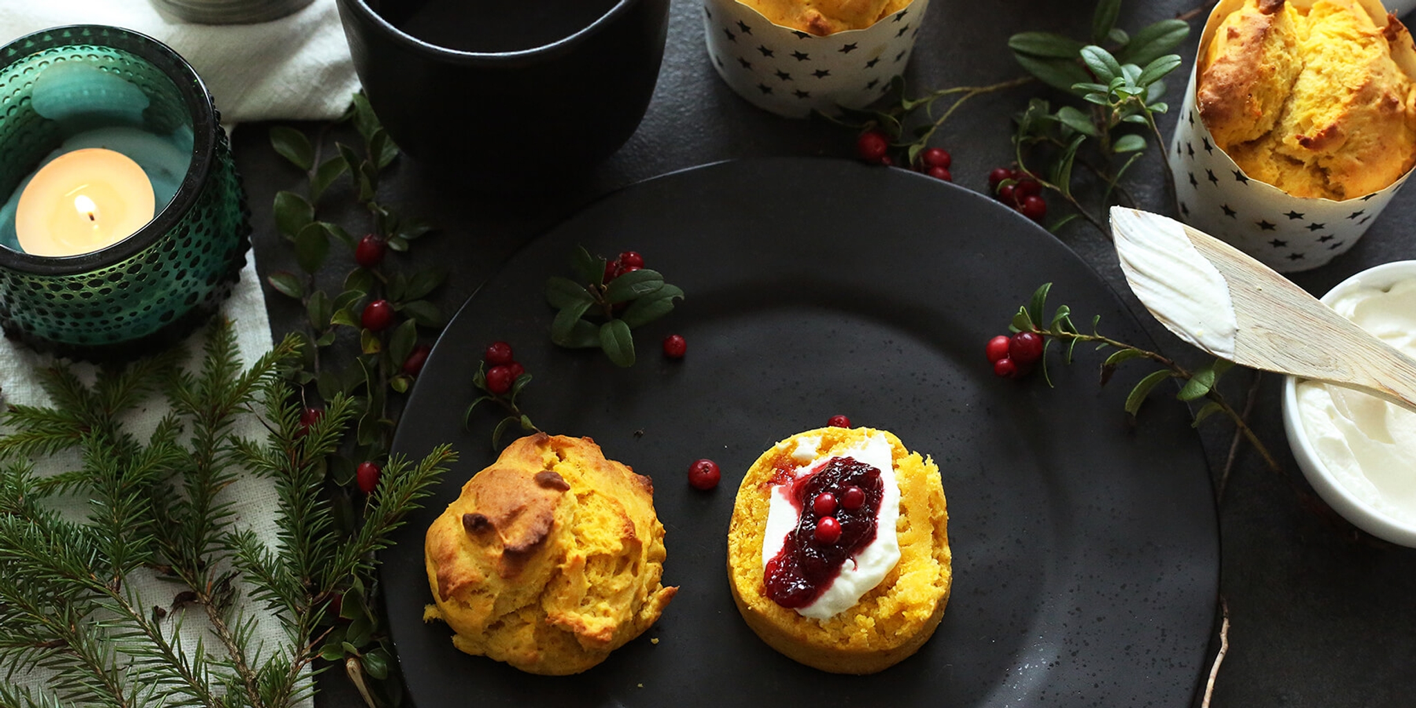 Safran scones med syltetøy på en svart tallerken med granbar og telys rundt