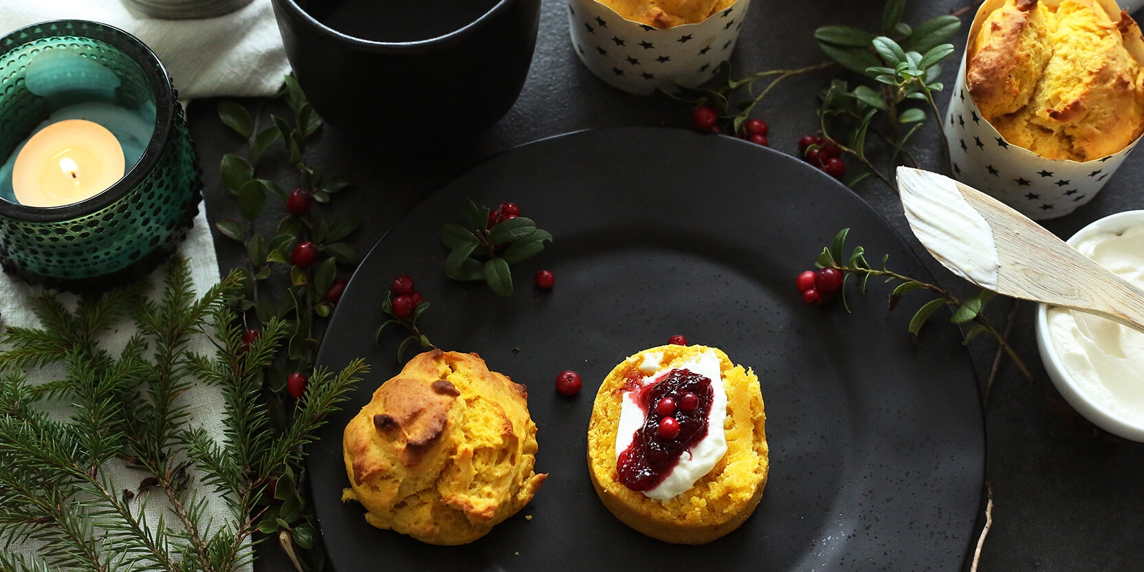Safran scones med syltetøy på en svart tallerken med granbar og telys rundt