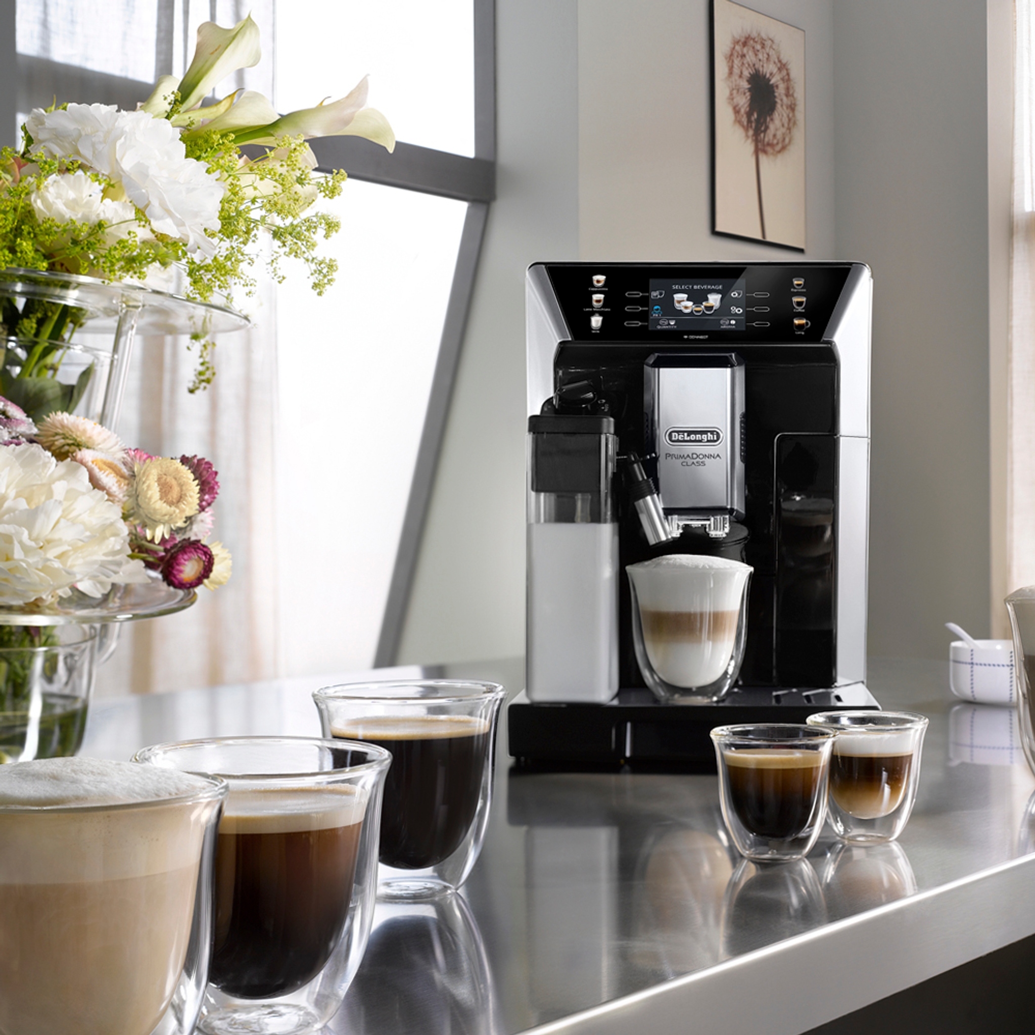 Latteglas på bänk vid en kaffemaskin med skummig latte i