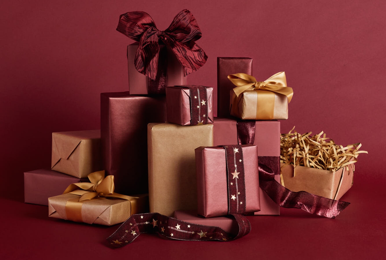 En trave presentaskar inslagna i nyanser av rött, rödbrunt och guld mot en mörkröd bakgrund.