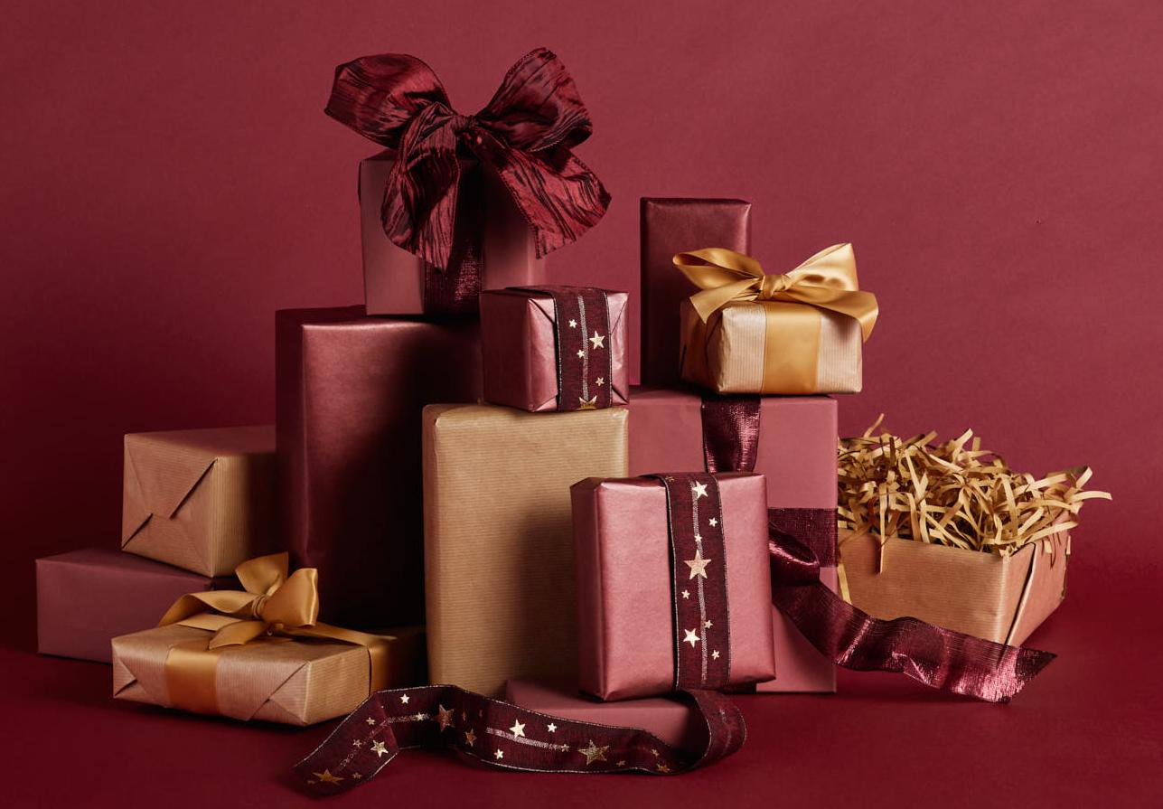 En trave presentaskar inslagna i nyanser av rött, rödbrunt och guld mot en mörkröd bakgrund.