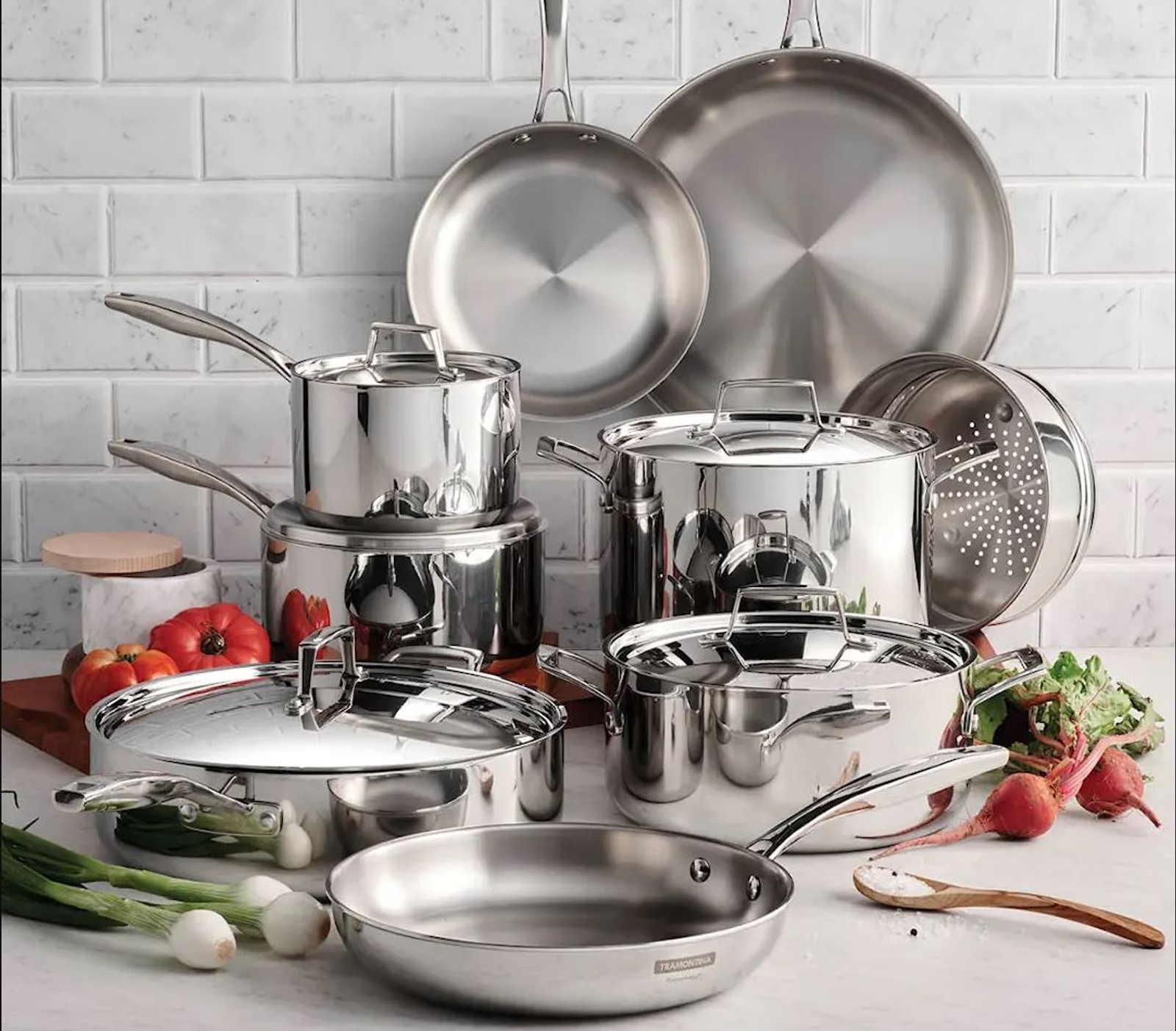 a bunch of stainless steel pots and pans are sitting on a counter next to vegetables .