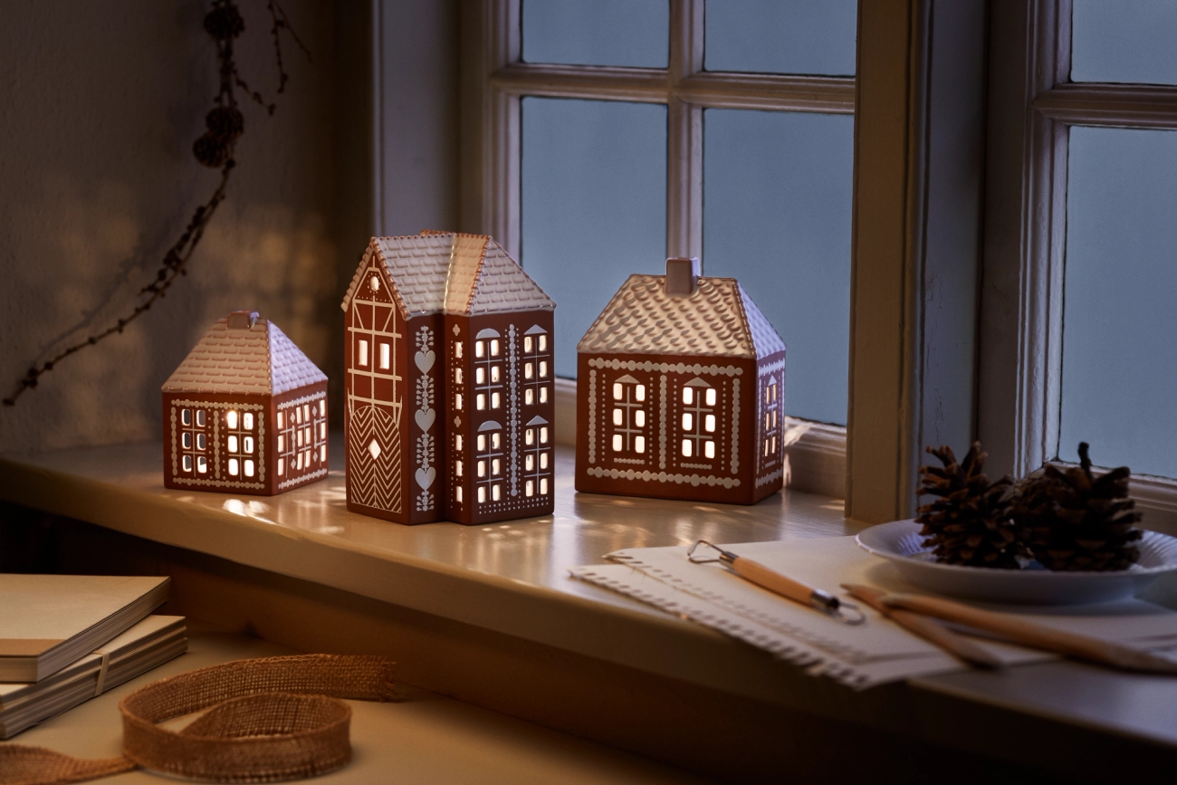 Ljuslyktor i form av hus och pepparkakshus i fönstret