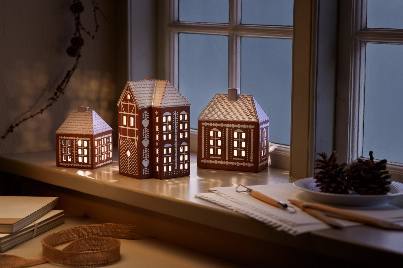 Ljuslyktor i form av hus och pepparkakshus i fönstret