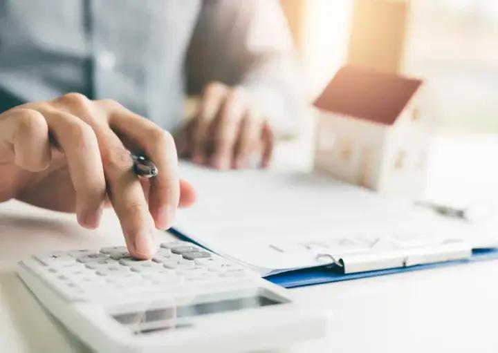 Homem calculando condições de refinanciamento de imóvel.