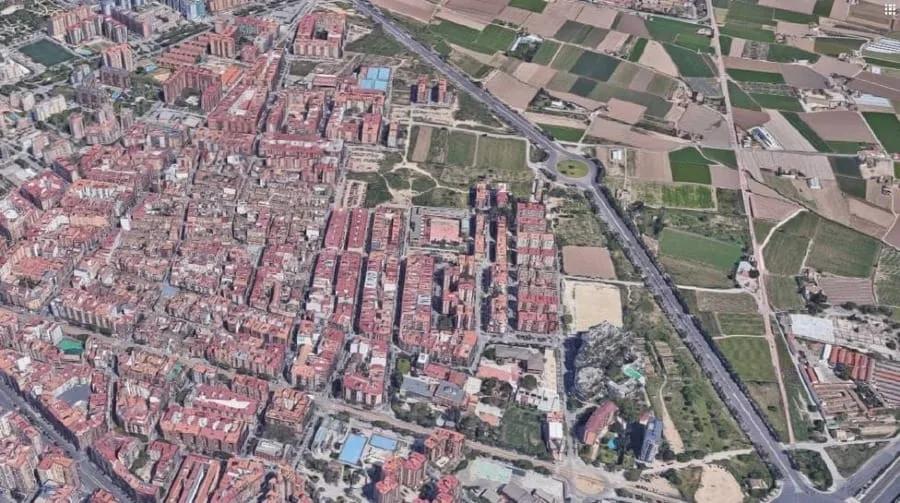 Periferia de Valência encontrando a huerta Vista aérea da periferia de Valência com blocos de apartamentos à esquerda e campos agrícolas à direita, separados por uma avenida