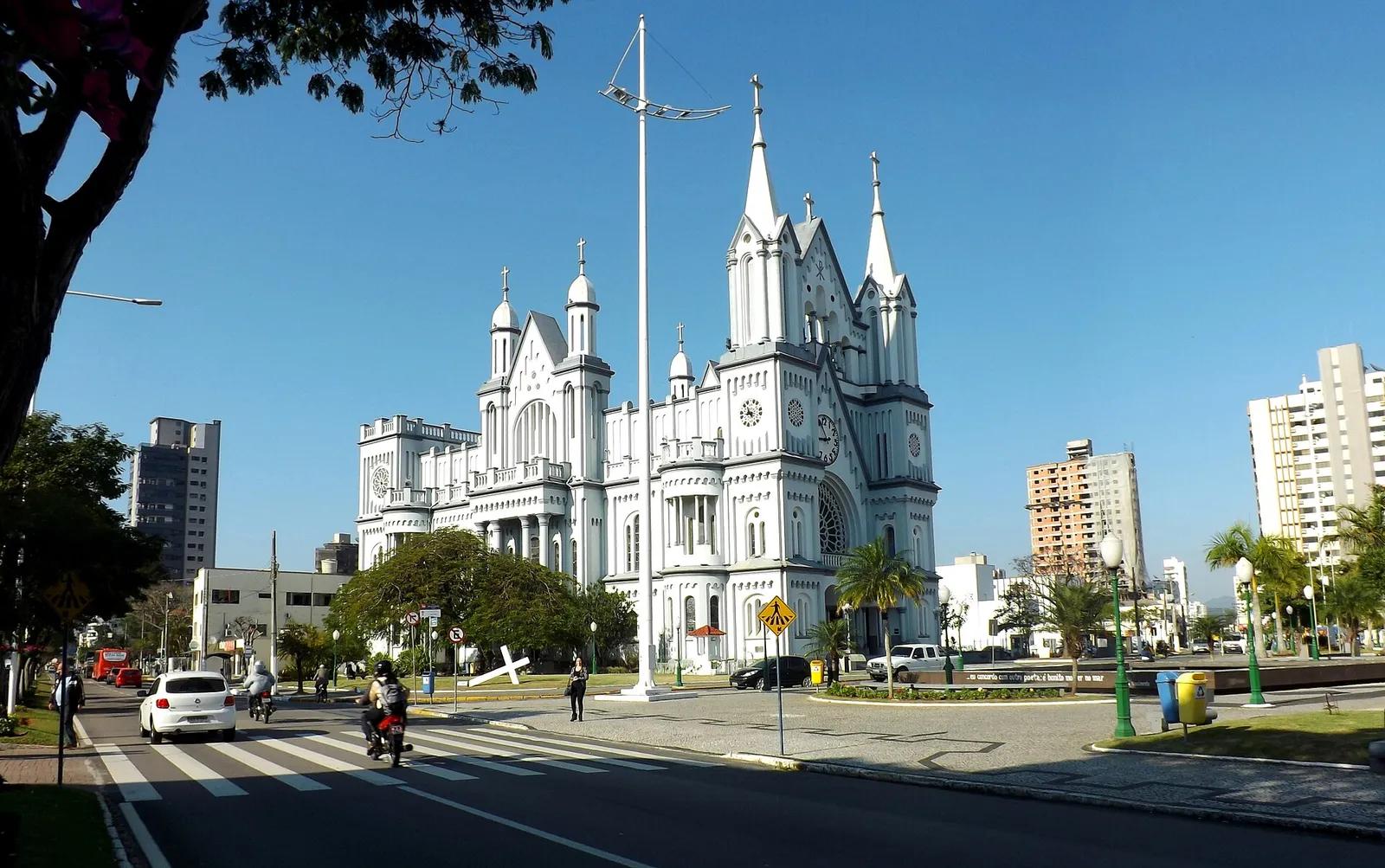 Igreja Matriz de Itajaí Igreja Matriz do Santíssimo Sacramento, em Itajaí, branca e em estilo neogótico, com céu azul e a praça em frente