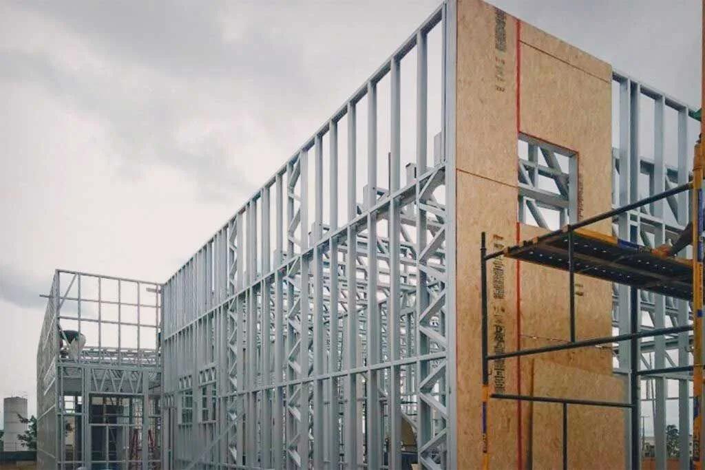 Paredes de steel frame com parte dos painéis já fechada com placas de OSB e andaime ao lado