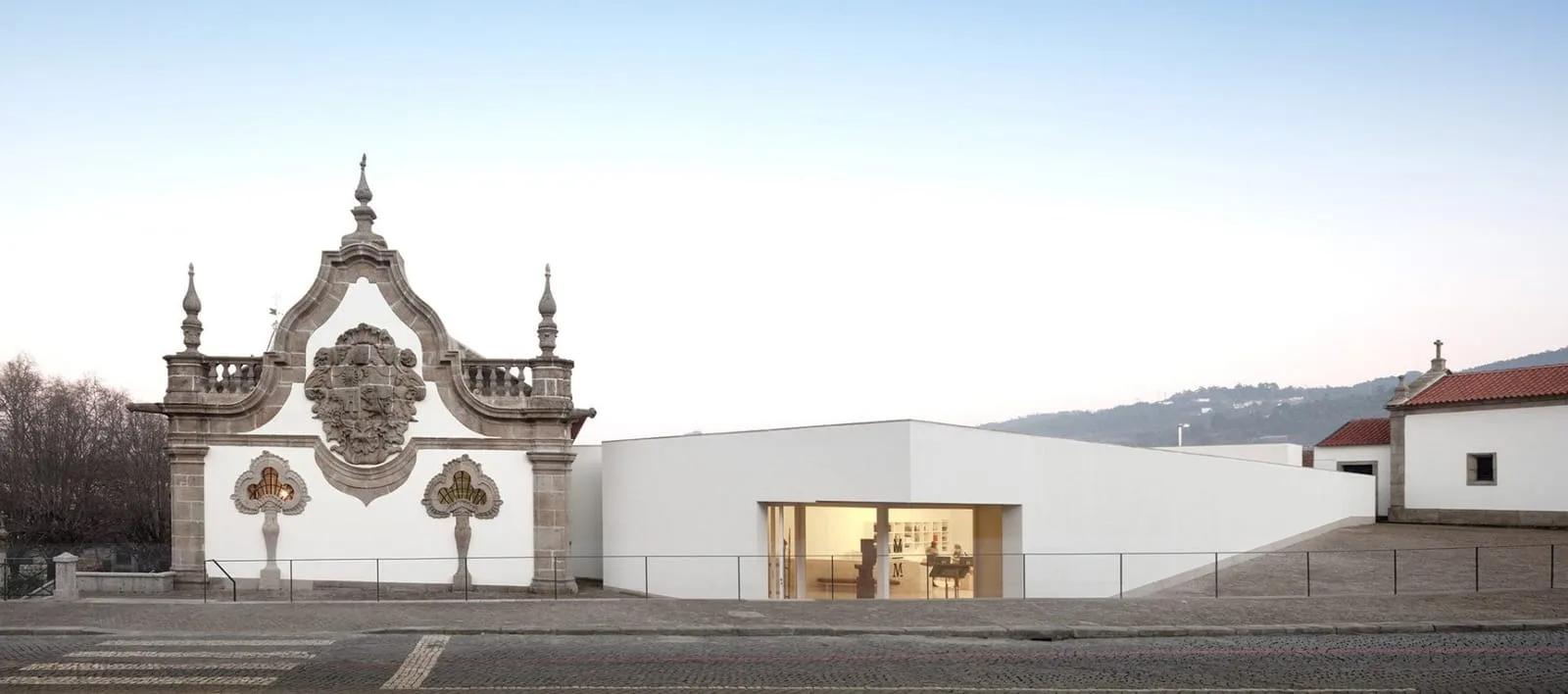 Portal barroco de pedra ao lado do volume branco do Museu Abade Pedrosa, em Santo Tirso