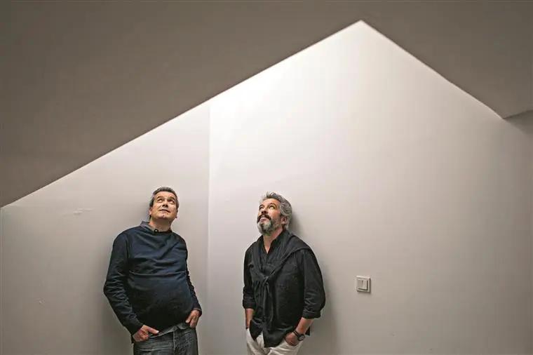 Os irmãos Manuel e Francisco Aires Mateus em pé sob um teto branco inclinado