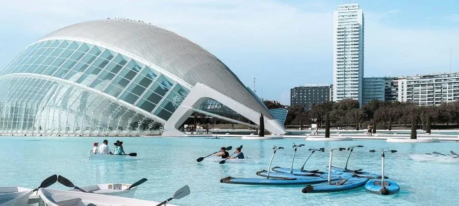 O Hemisfèric com sua casca envidraçada, pedalinhos e caiaques no lago e um prédio alto ao fundo