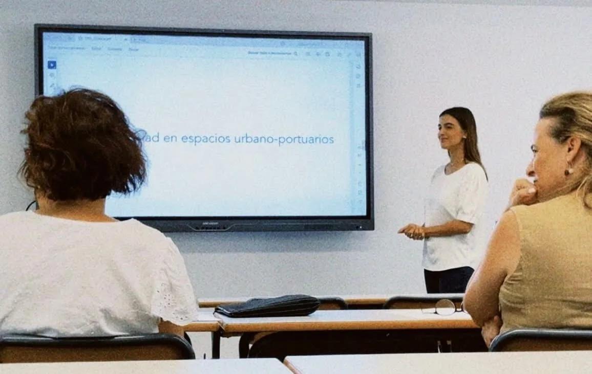 Apresentação do TFG Estudante apresenta um trabalho projetado em uma tela para uma banca sentada em sala de aula