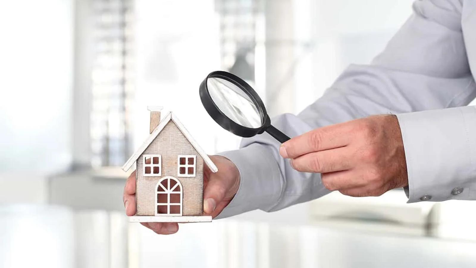 Casa sendo observada por lupa como analogia ao processo de avaliação imobiliária.