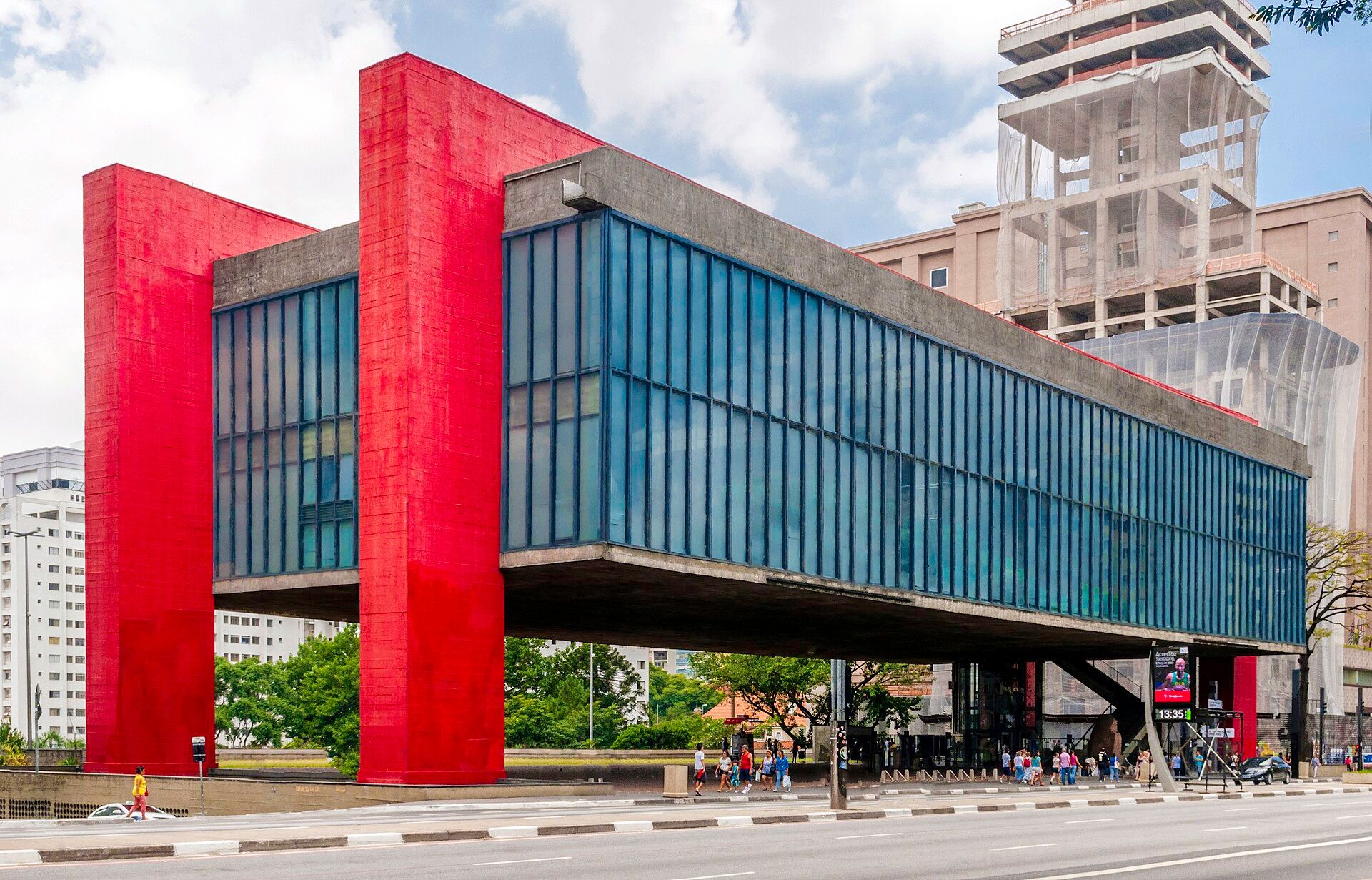 MASP visto da Avenida Paulista: bloco de concreto e vidro suspenso por dois pórticos vermelhos sobre o vão livre