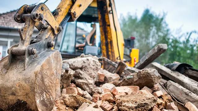 Trator demolindo casa desapropriada para obras de infraestrutura da cidade