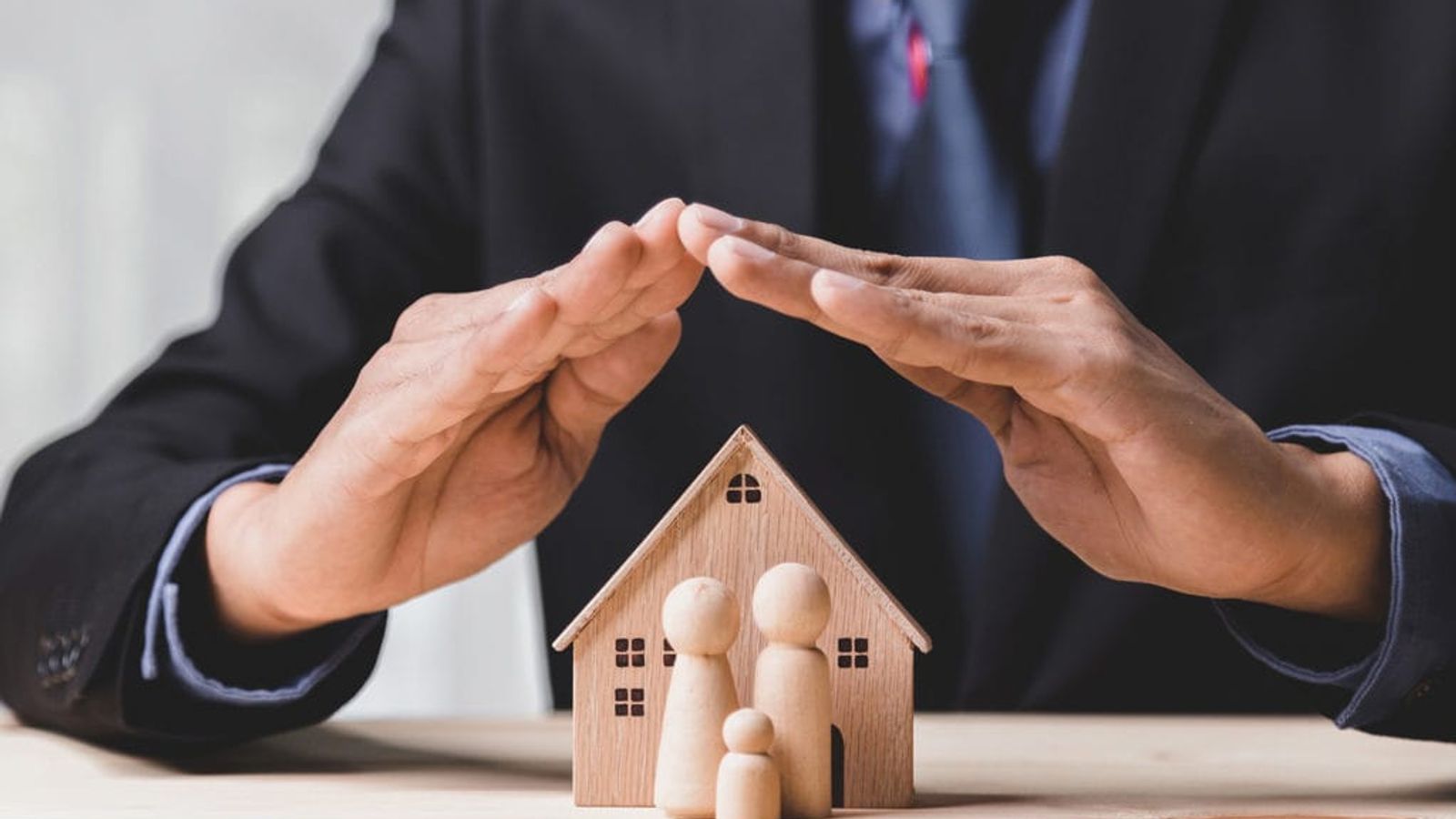 Homem cuidando da maquete de uma casa.