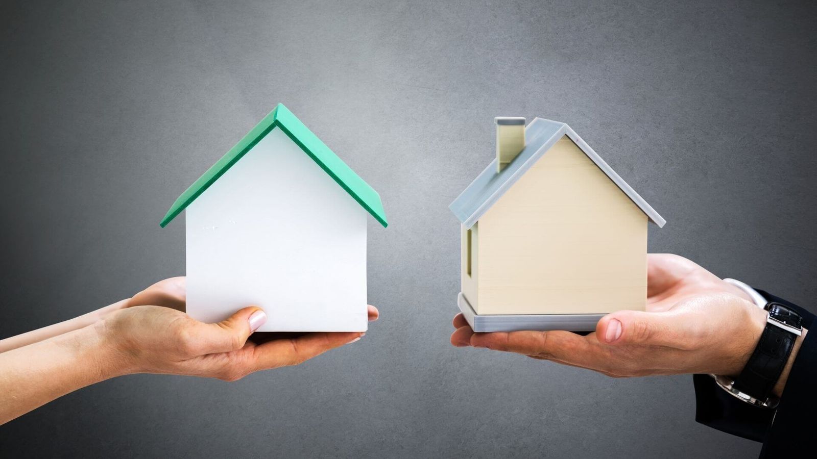 Duas pessoas segurando duas maquetes de casas.
