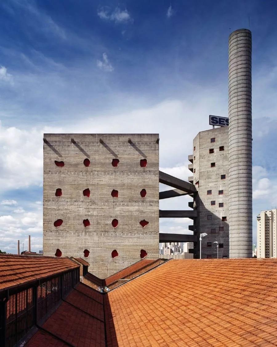 Torres de concreto do Sesc Pompeia com janelas vermelhas irregulares e a caixa-d’água cilíndrica