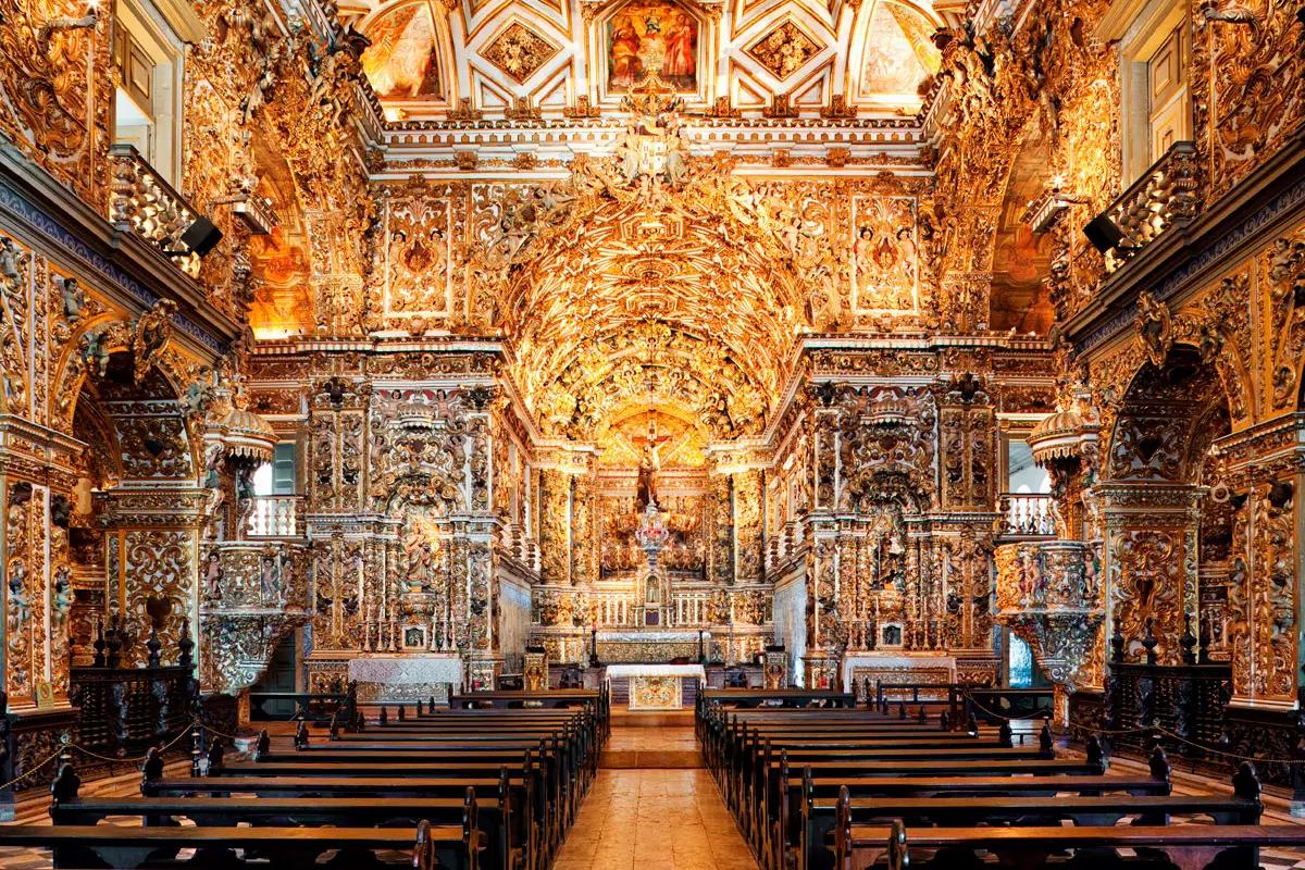 Interior de igreja barroca com talha dourada Interior de igreja barroca com altares de talha dourada e bancos de madeira