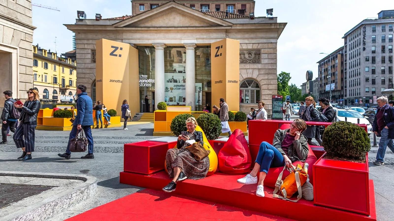 Instalação de design em um pátio de Milão durante o Fuorisalone, com visitantes circulando
