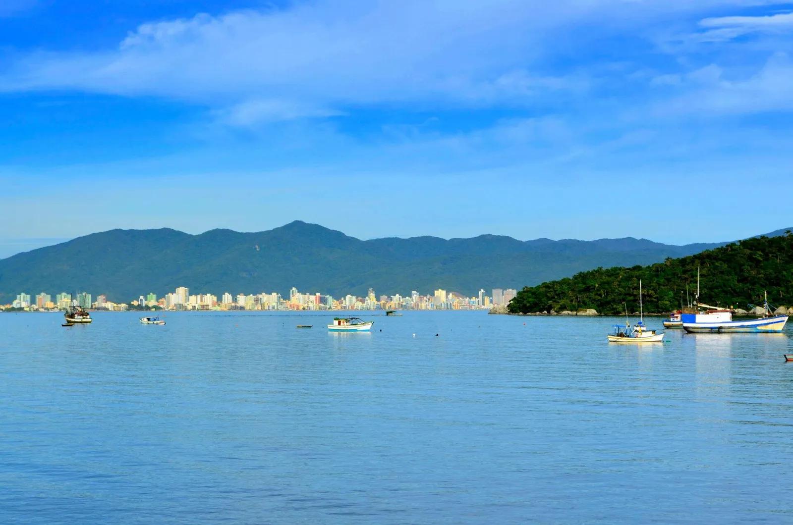 Enseada de Itapema Enseada de Itapema com barcos na água azul, prédios na orla e morros ao fundo