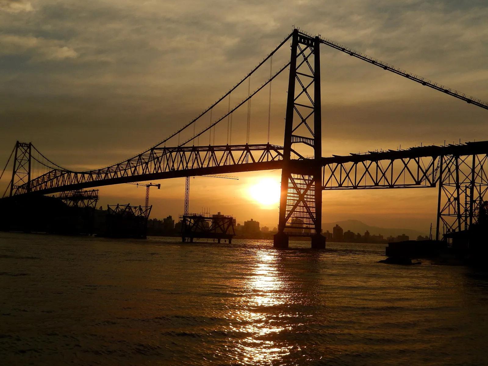 Ponte Hercílio Luz, Florianópolis Ponte Hercílio Luz, em Florianópolis, ao pôr do sol, com o sol atrás de uma das torres e o reflexo na água