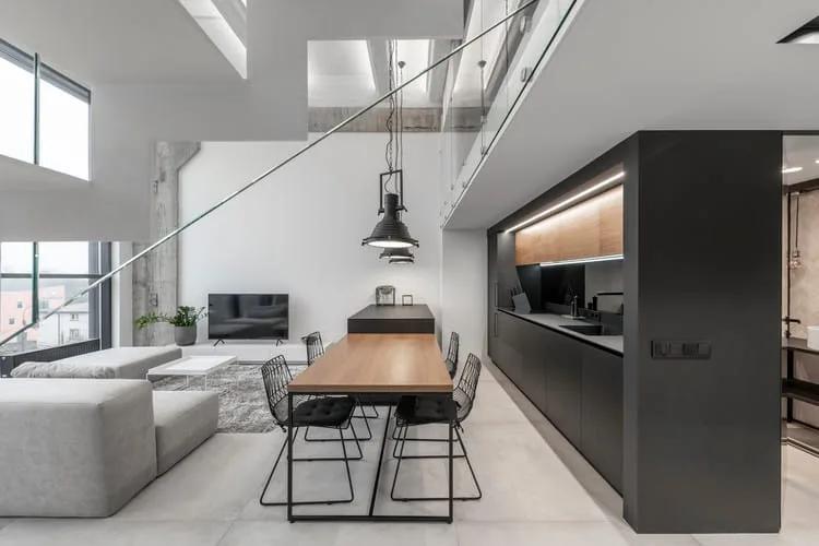 Estilo de vida minimalista Apartamento de pé-direito duplo com cozinha preta, mesa de madeira e escada metálica