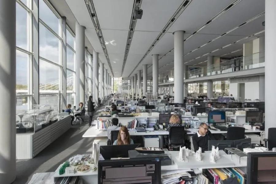 Escritório internacional de arquitetura Grande escritório de arquitetura de planta livre, com pé-direito alto, colunas e dezenas de estações de trabalho
