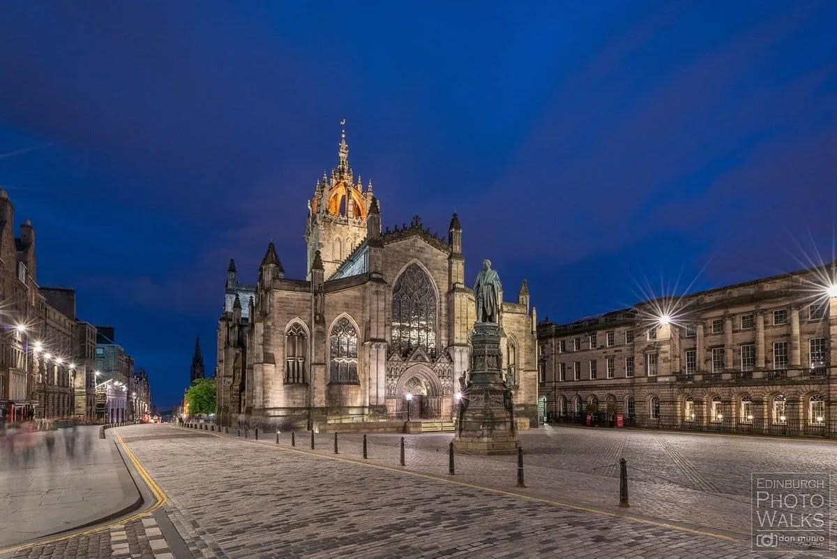 Catedral de St. Giles iluminada à noite, com a torre coroada de arcos de pedra, na praça da Royal Mile