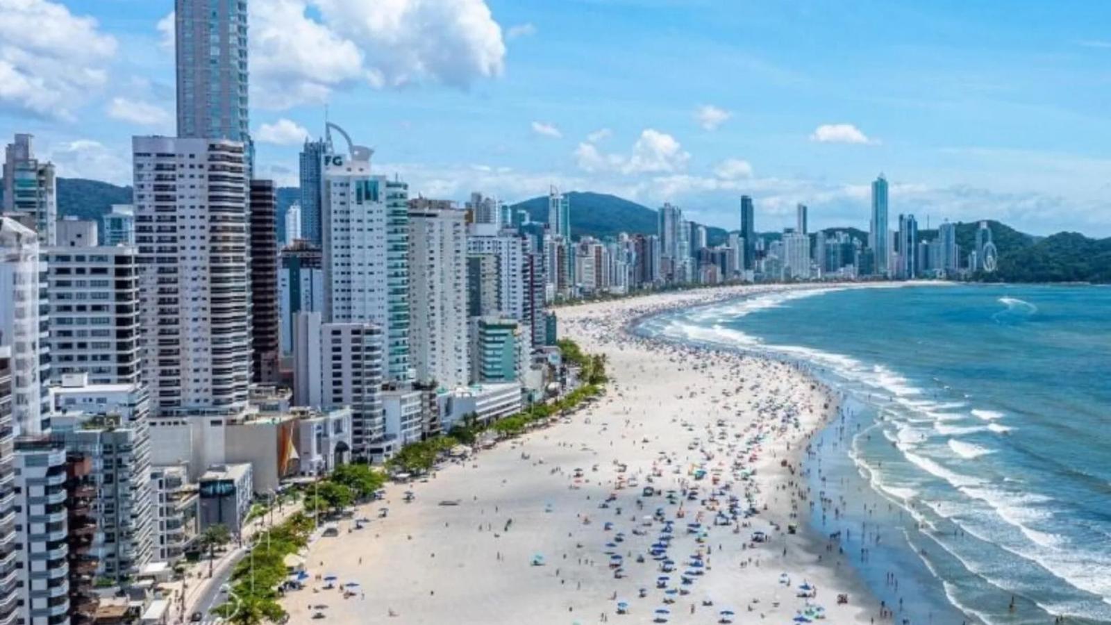Praia Central de Balneário Camboriú vista do alto, com a faixa de areia, o mar e a fileira de prédios altos na orla