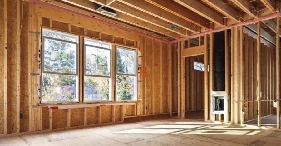 Interior de casa em wood frame em obra, com montantes de madeira, chapas de OSB e janelas instaladas