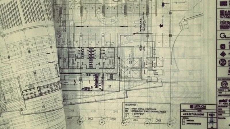 Folhas de plantas técnicas de um edifício sobrepostas, com carimbo e desenhos de arquitetura