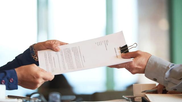 Folhas de contrato sendo entregues de uma pessoa para outra