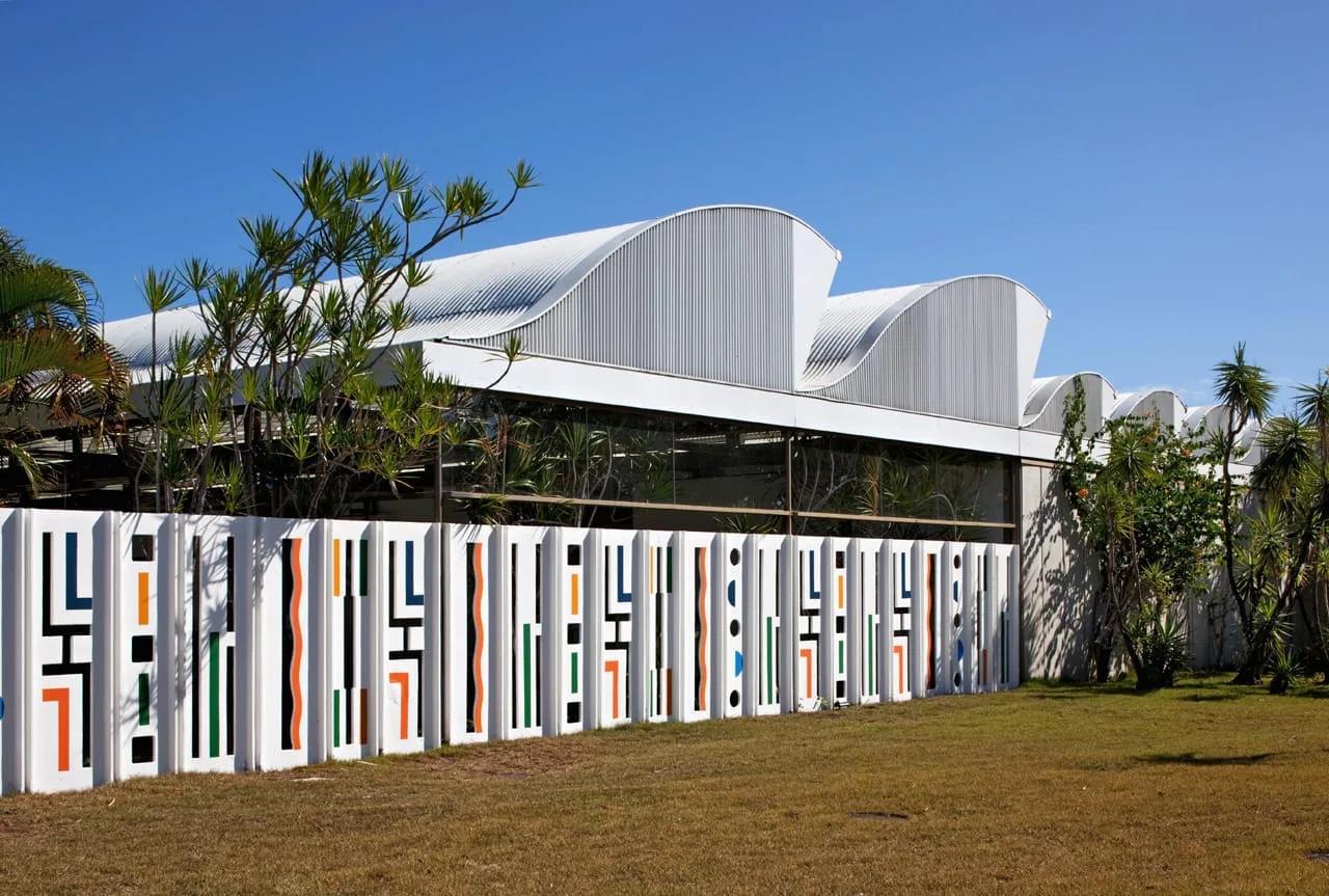 Hospital Sarah com coberturas curvas metálicas e muro de painéis coloridos em primeiro plano