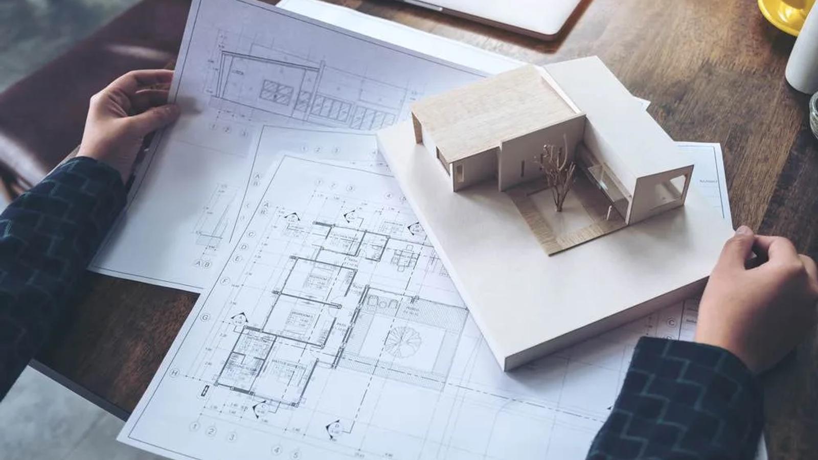 Imóvel sendo avaliado por especialista através de plantas, planilhas e maquete.