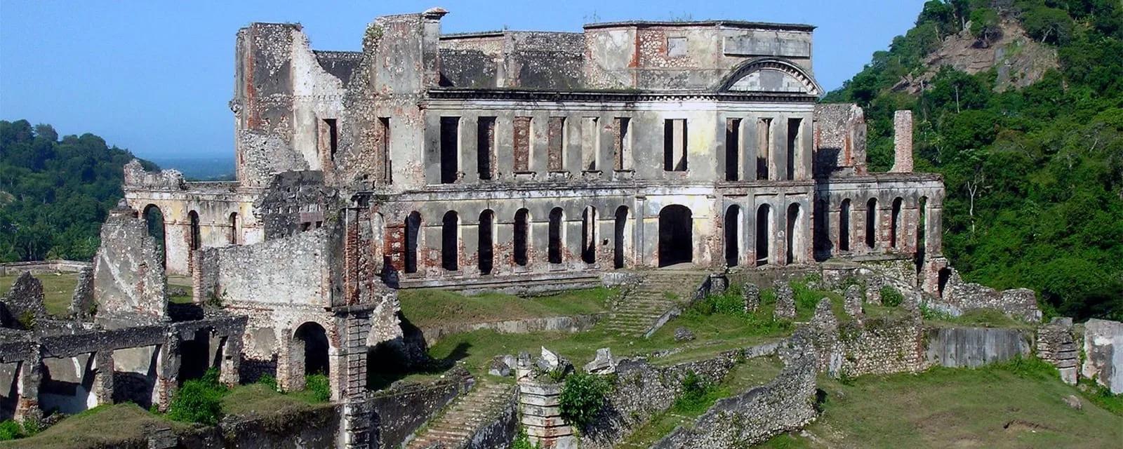 Ruínas de um palácio de alvenaria em meio a morros cobertos de vegetação